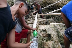 People use tubes to collect water from a mountain on September 28 in San Juan, Puerto Rico